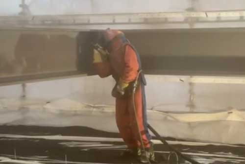 Orangeklädd arbetare som utför blästring