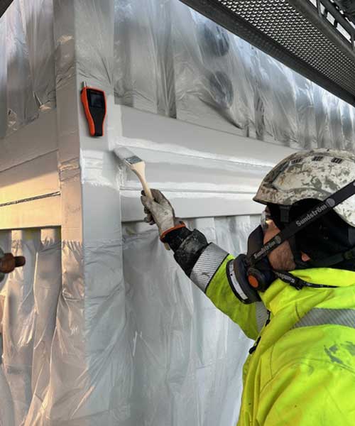 Arbetare med hjälm och mask som målar